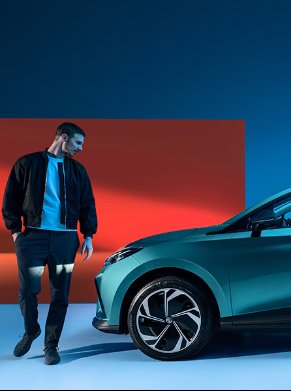 Man standing beside a teal electric car.