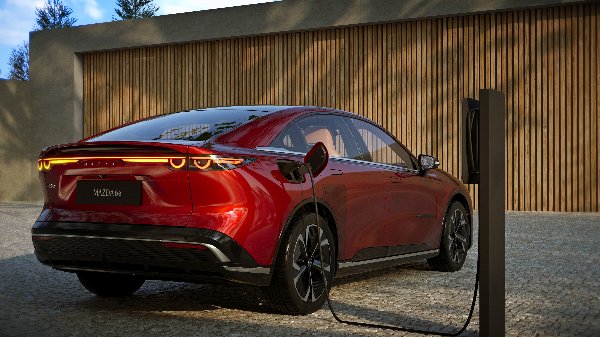 Red Mazda 6e electric car charging at a station.